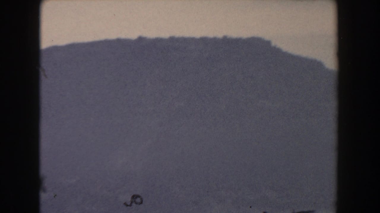 Grey mountain silhouette fills the frame below a muted foggy sky.