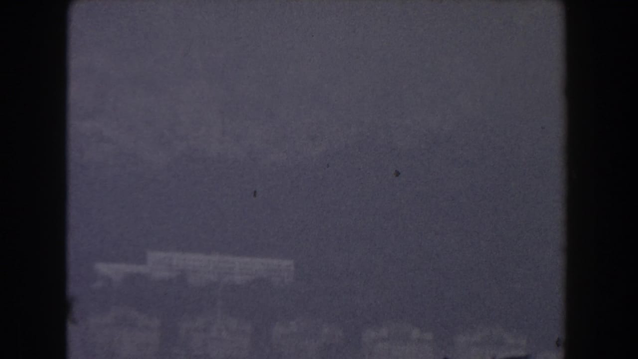 Hazy distant shoreline across dark blue water, framed by black film borders.