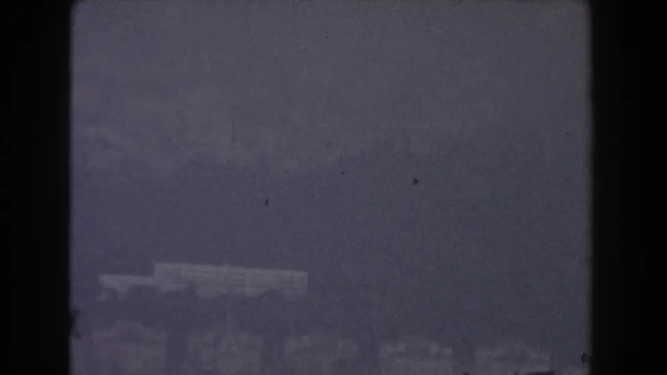 1959 8mm view of Gibraltar's distant coastline across rippling water, with soft focus and dark frame edges.