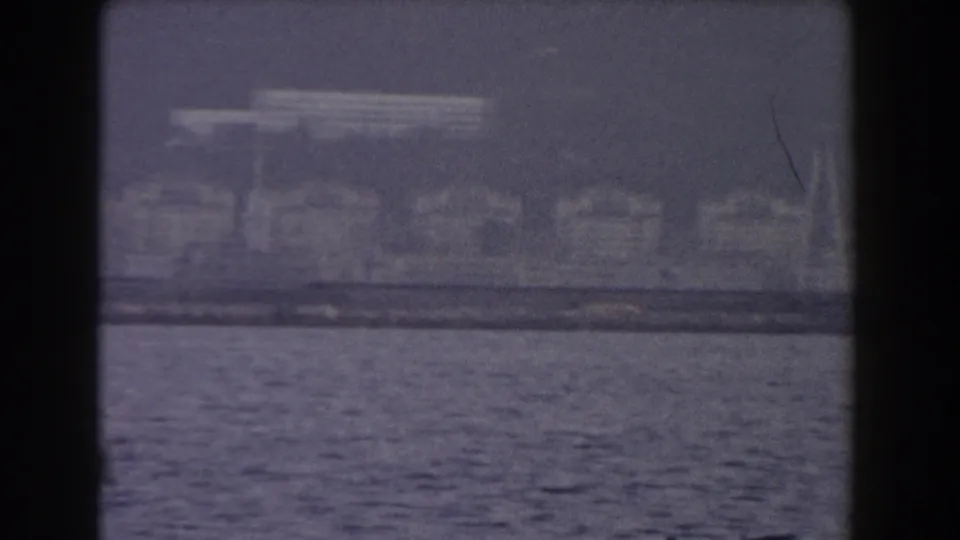 Late-frame 1959 8mm view of Gibraltar's shoreline, with calm rippling sea and soft waterfront detail.