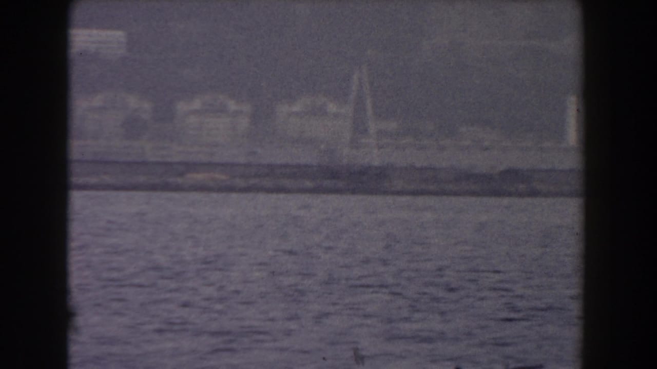 1959 Gibraltar 8mm frame showing hazy shoreline and water from a boat-facing viewpoint.