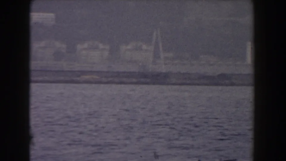 1959 Gibraltar 8mm frame showing hazy shoreline and water from a boat-facing viewpoint.