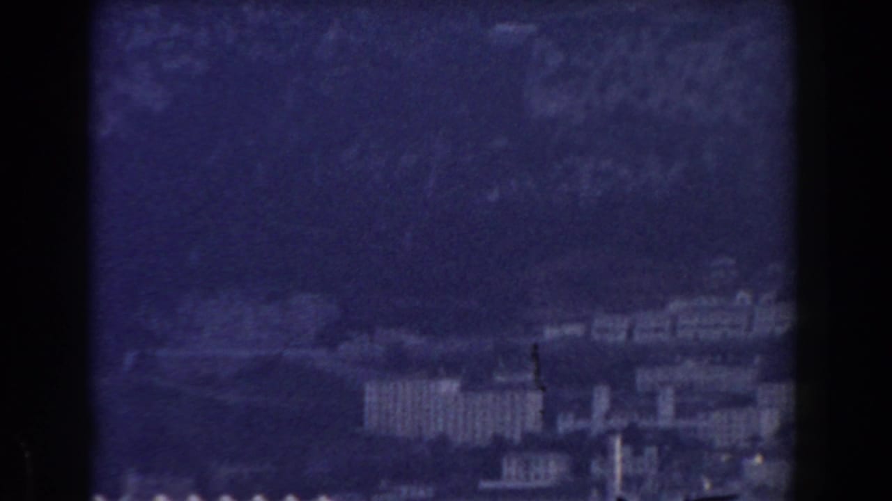 Soft 1959 Gibraltar city view with pale buildings clustered below the Rock in a blue-purple cast.