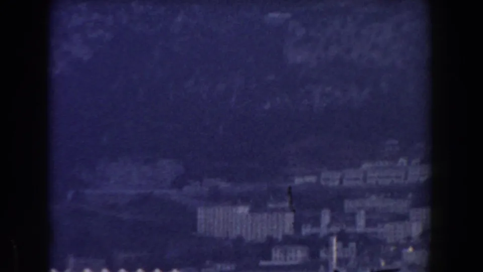 Soft 1959 Gibraltar city view with pale buildings clustered below the Rock in a blue-purple cast.