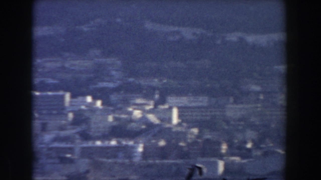 1959 Gibraltar panorama with scattered white buildings, hillside roads or terraces, and the mountain rising behind the city.