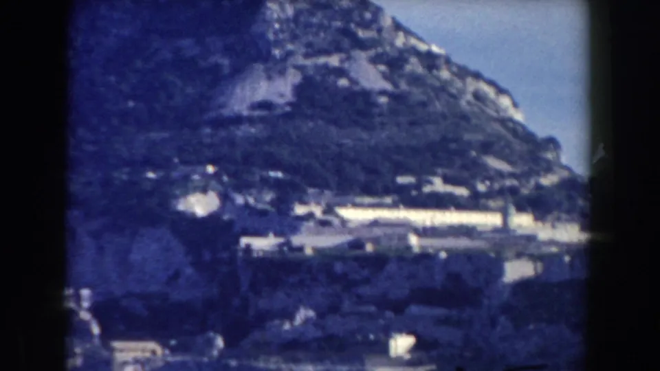 1959 Gibraltar frame with hillside buildings at the base of the Rock and soft blue 8mm color.