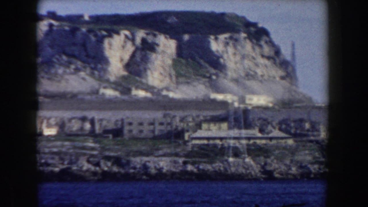 Rocky Gibraltar shoreline with clustered buildings and a steep cliff behind them.