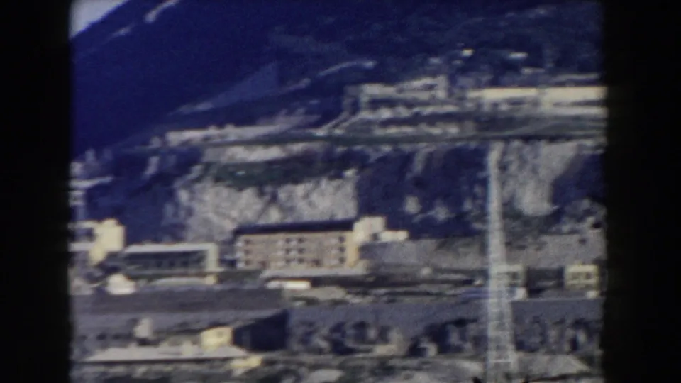 1959 Gibraltar home-movie frame showing town buildings at the base of the Rock, with soft focus and visible 8mm gate edges.