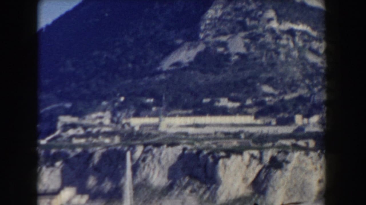 Rocky cliff and lower town structures seen from a distance.
