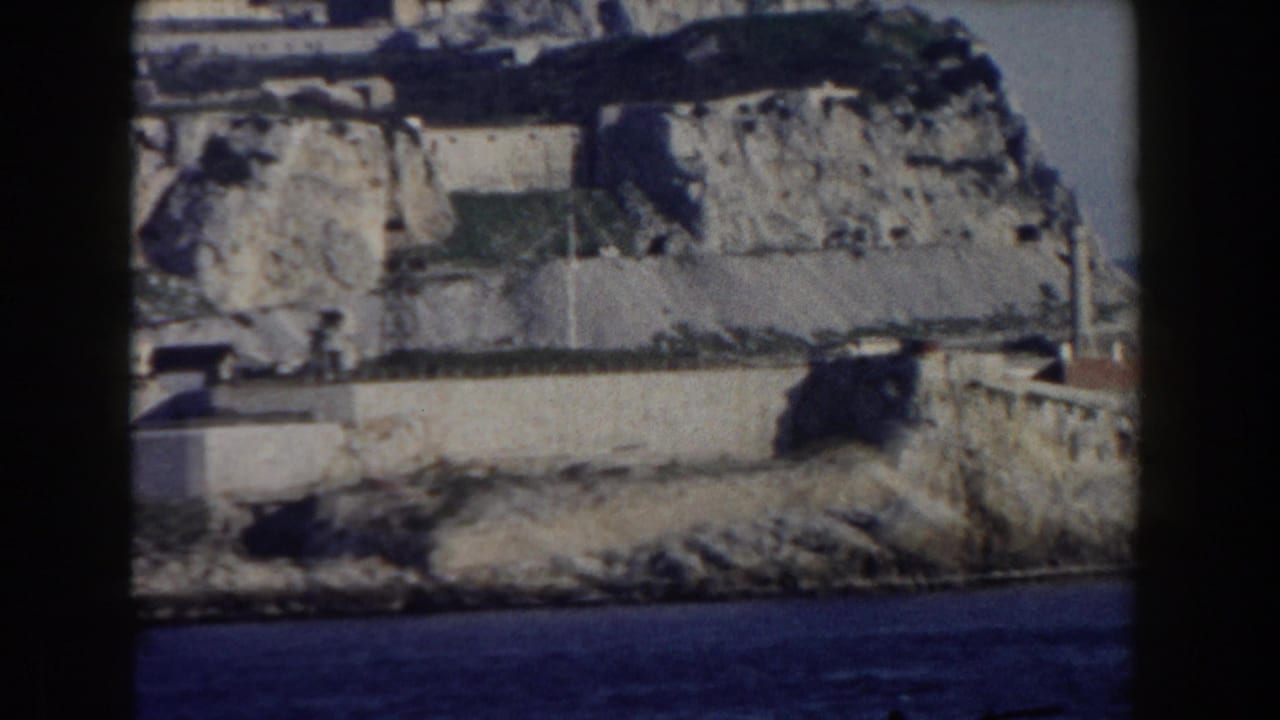 Coastal fortification walls and rocky shore beneath the limestone cliffs.