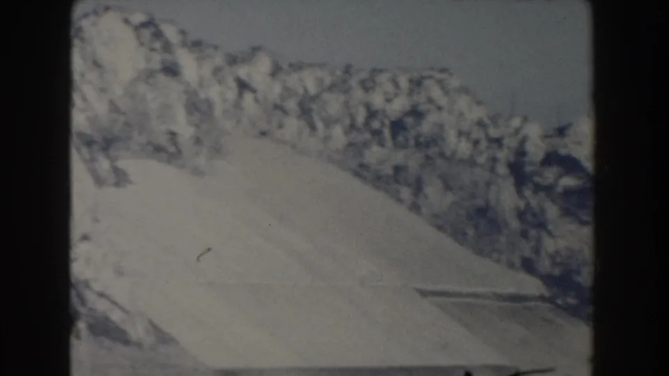 1959 Gibraltar home-movie frame showing a pale limestone cliff rising above the sea with soft focus and dark film borders.
