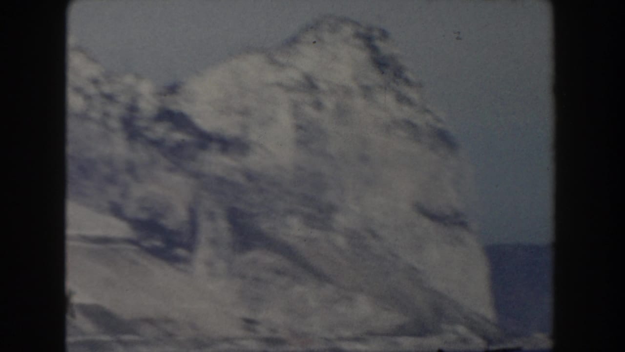 Large pale cliff formation with sea and hazy sky in a soft 8mm frame.