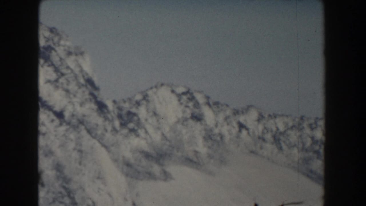 Snow-covered mountain ridge under a pale sky with dark rocky shadows.