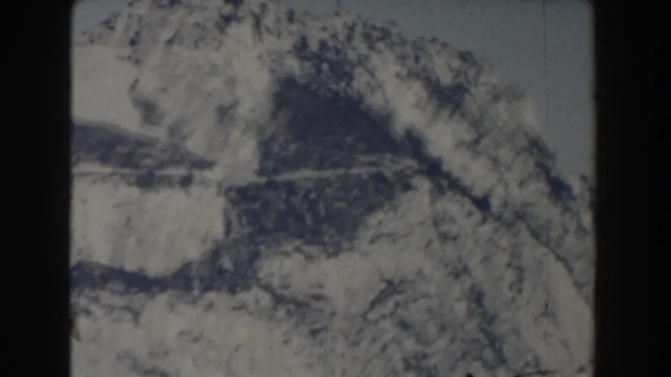 1959 Gibraltar-labeled 8mm frame showing a shadowed snow-covered slope and jagged mountain forms.