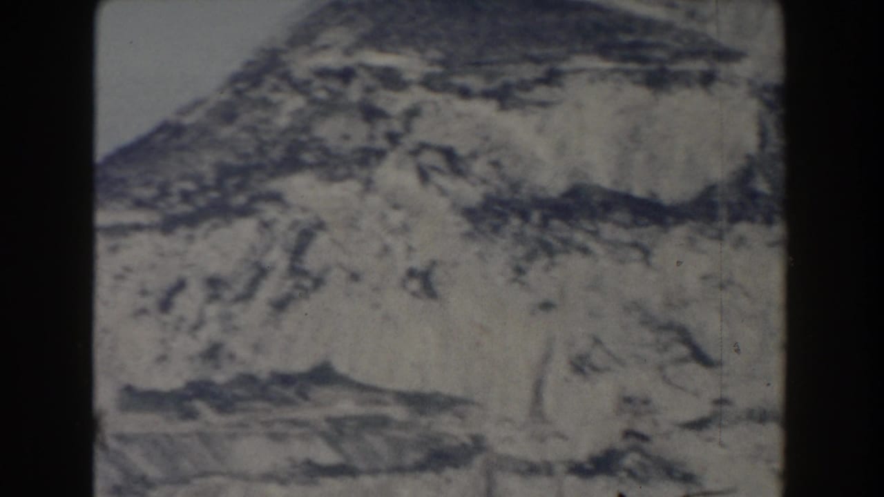 1959 8mm view of Gibraltar's pale rocky cliff face and lower slopes, framed by dark film borders.