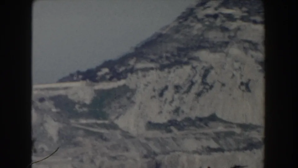 Gibraltar hillside in 1959 home-movie footage, showing steep pale rock layers and a lower road or wall-like line.