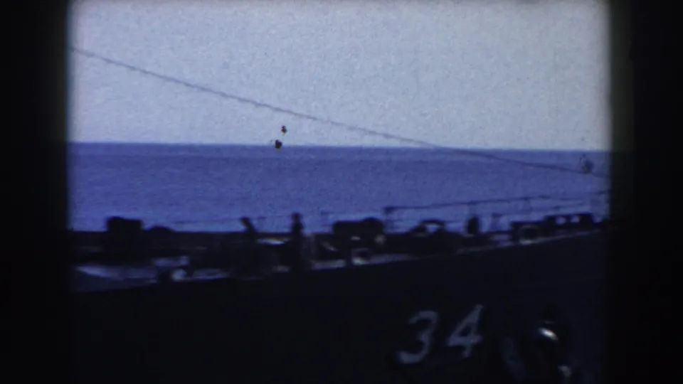 1959 Gibraltar 8mm frame showing a docked warship with hull number 34, crew silhouettes along the deck, and open water behind it.