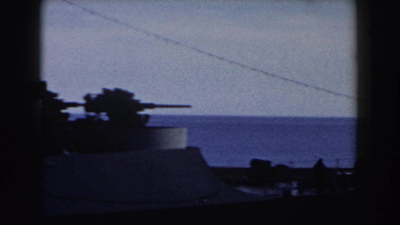 Silhouetted gun turret and ship structure against the sea horizon.