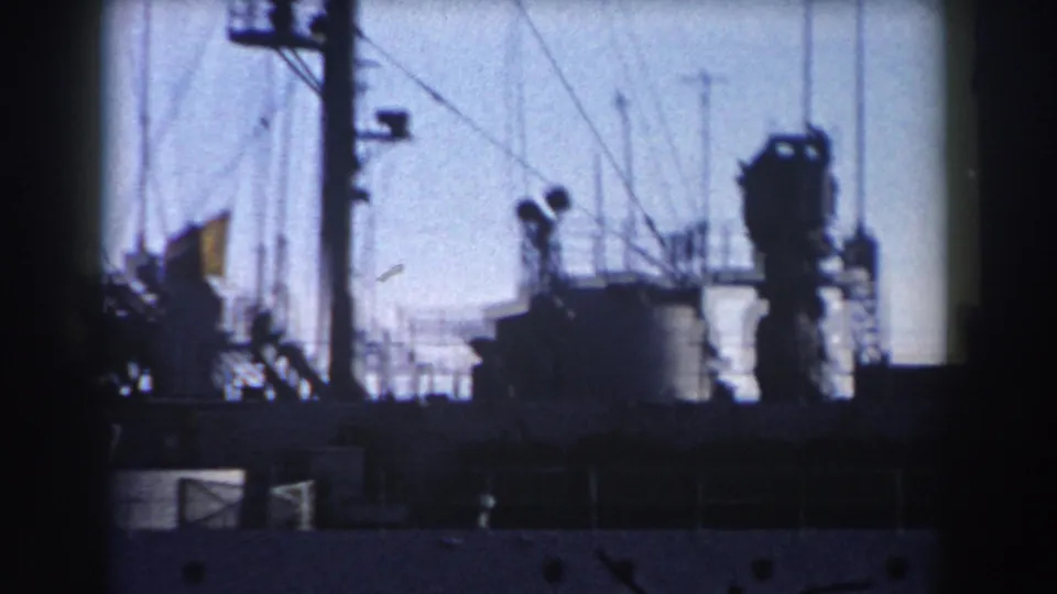 1959 Gibraltar 8mm frame showing a dark ship mast area, antennas, and partial superstructure under a blue-gray sky.