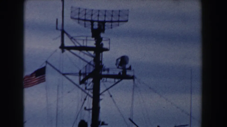 1959 Gibraltar 8mm frame showing a ship mast topped by radar equipment, with rigging, platforms, and a U.S. flag visible.