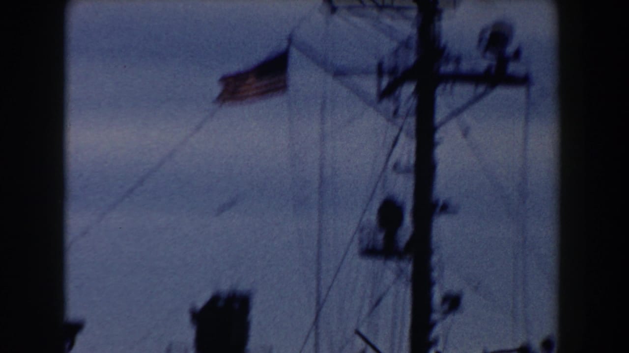 U.S. flag and ship mast seen in soft focus against a blue sky.