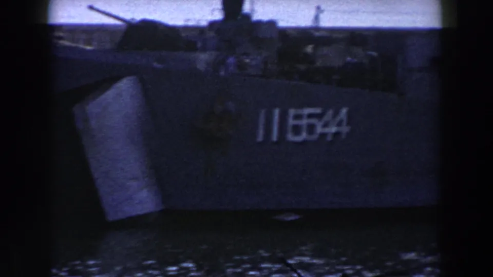 1959 Gibraltar frame showing the bow of a U.S. Navy vessel with hull number 1154, filmed from across the harbor water.