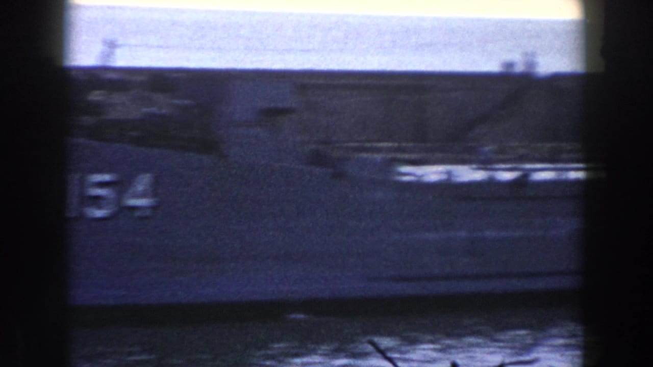 Numbered naval vessel in harbor water, partly obscured by dark contact-sheet borders.