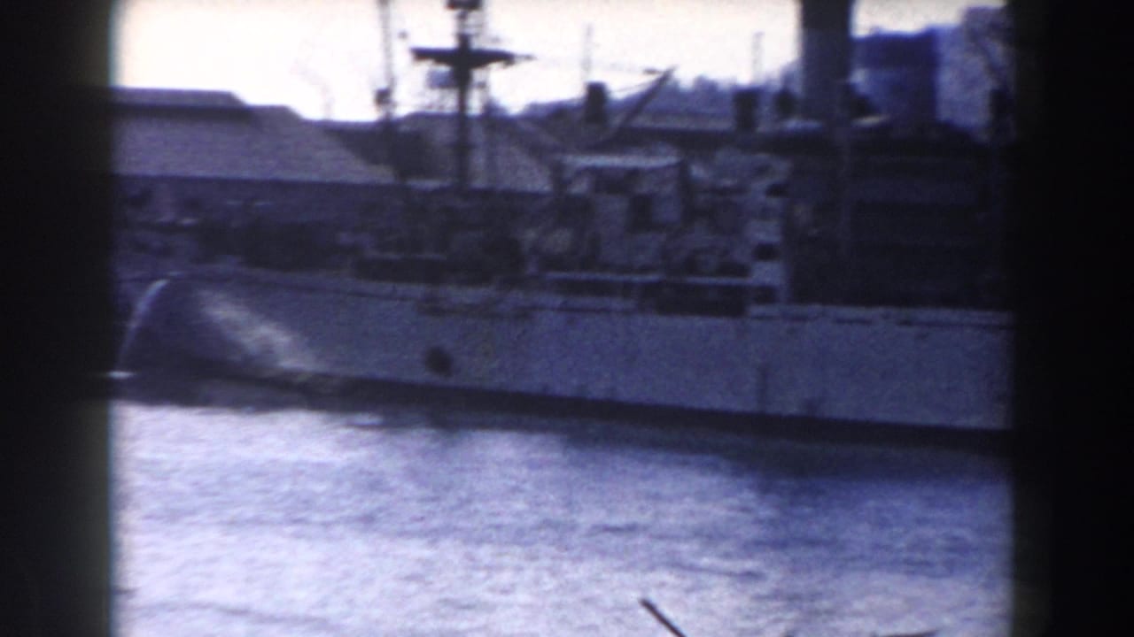 Grainy 1959 Gibraltar harbor view showing a naval vessel across water with port buildings in the background.
