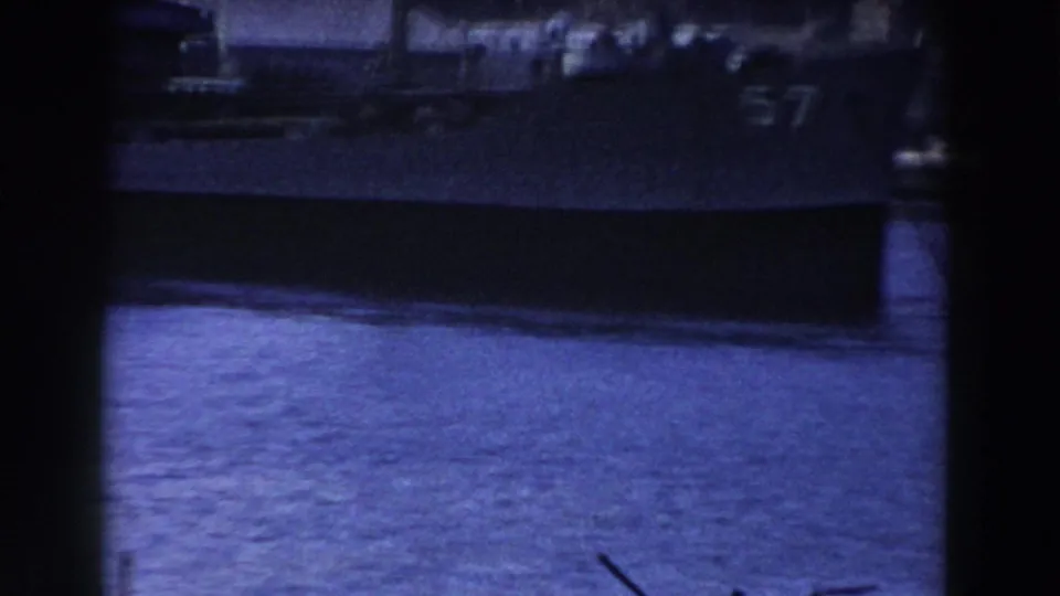 Blue-tinted 8mm frame showing the side of a naval vessel in Gibraltar harbor, with a partial hull number visible.