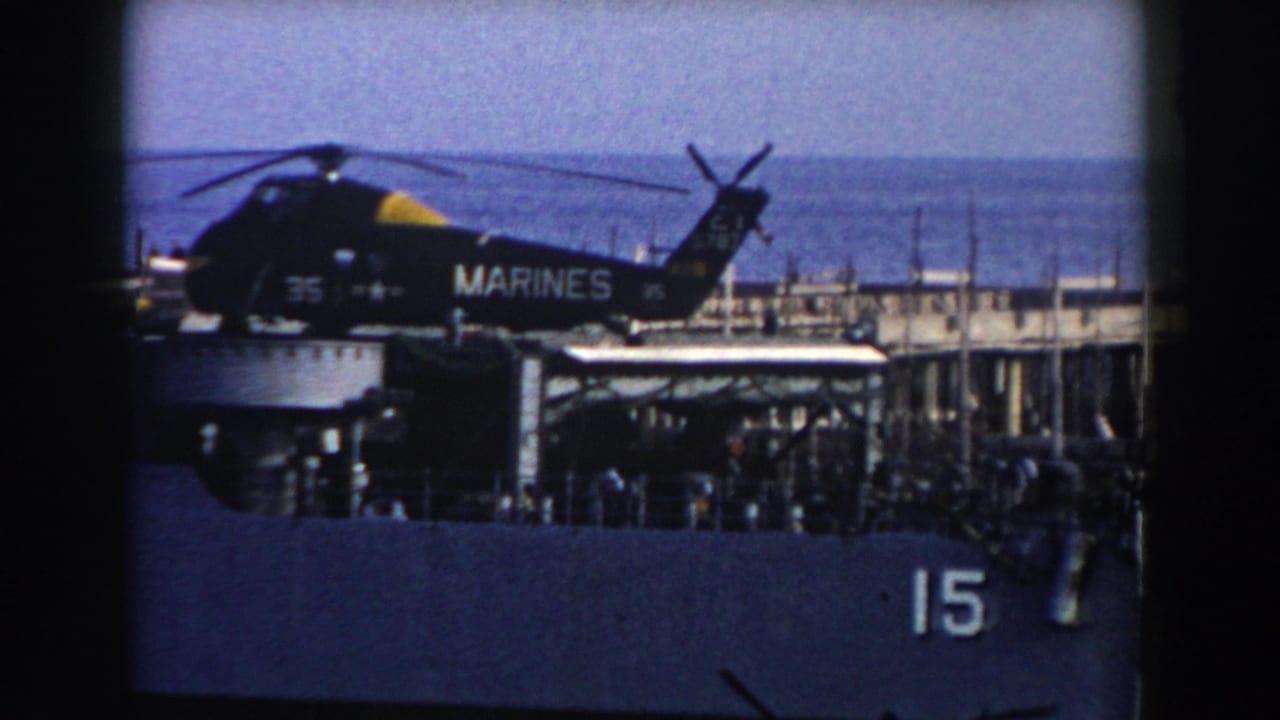 1959 8mm view near Gibraltar of a U.S. Marine Corps helicopter on a naval ship deck, with crew and blue sea in the background.