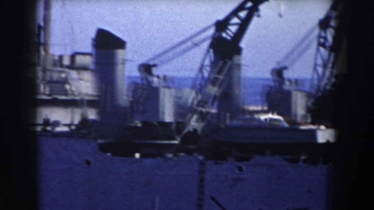 1959 Gibraltar harbor view with a grey ship, cranes, deck structures, and water in soft 8mm color.