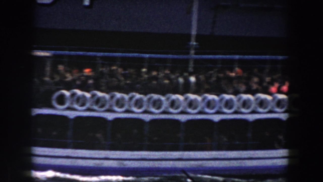 Side view of a crowded ferry deck lined with white life rings at night.
