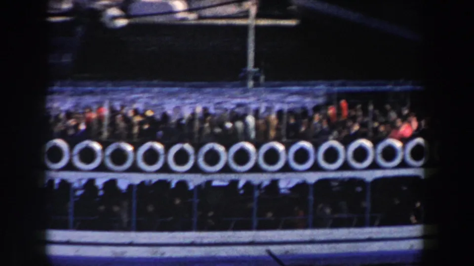 1959 Gibraltar 8mm frame showing a crowded ferry deck lined with white life preservers as passengers stand near the rail.