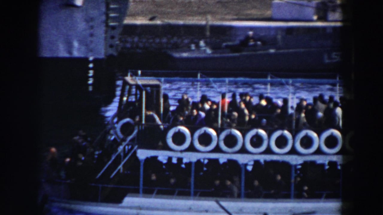 Ferry side with passengers clustered near the rail and life rings.