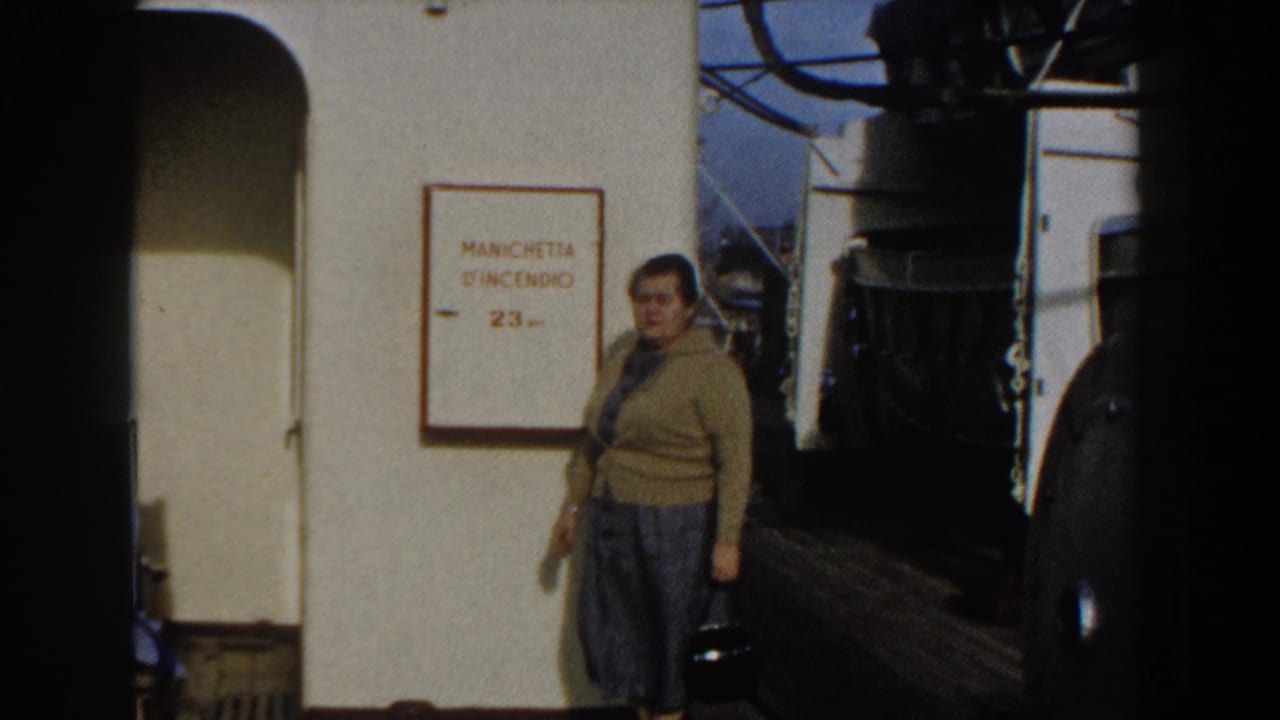 Woman with handbag standing on a ship deck near a fire-hose sign.