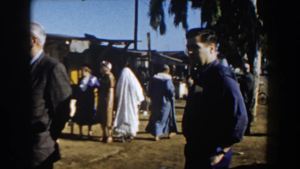 Casablanca 1959 home-movie frame showing people in mixed dress walking through a sunlit outdoor market area.