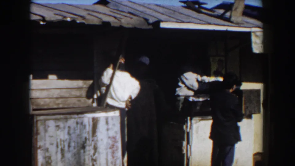 1959 Casablanca frame showing men gathered at a modest street stall, with a worn counter, metal roof, and shaded serving area.