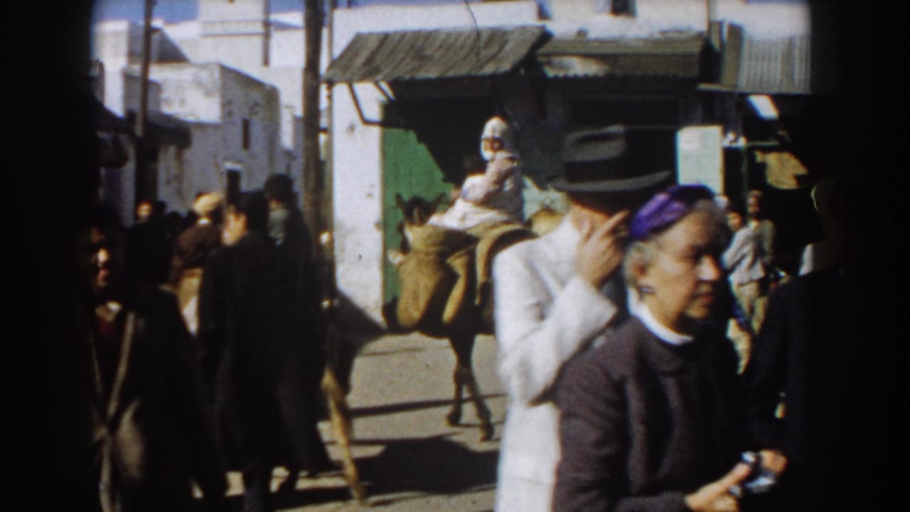 Crowded Casablanca street with pedestrians, a donkey rider, and a woman in a purple headscarf.