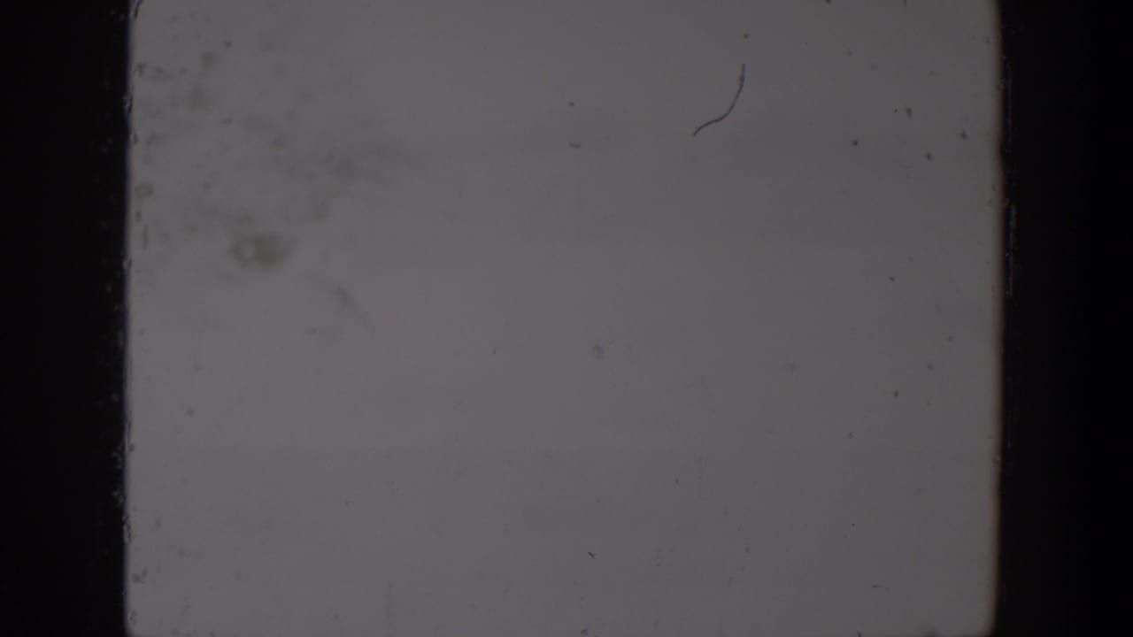Blown-out 1957 Lubbock 8mm frame showing pale exposure, black edge borders, dust specks and analog wear.