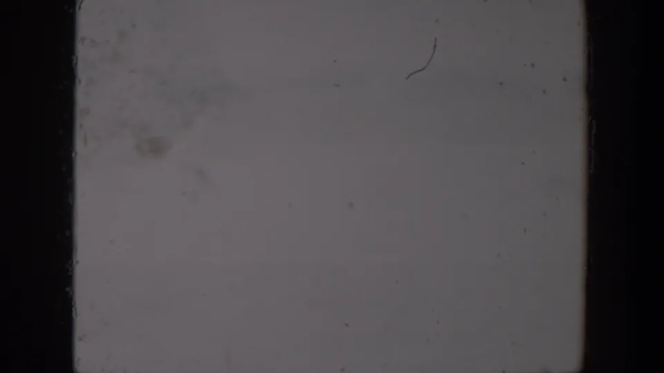 Blown-out 1957 Lubbock 8mm frame showing pale exposure, black edge borders, dust specks and analog wear.