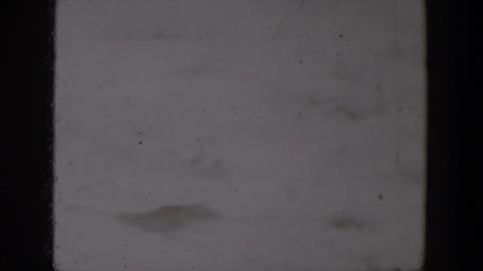 Blown-out 1957 Lubbock home-movie frame with heavy exposure, dark film edge and faint surface marks.