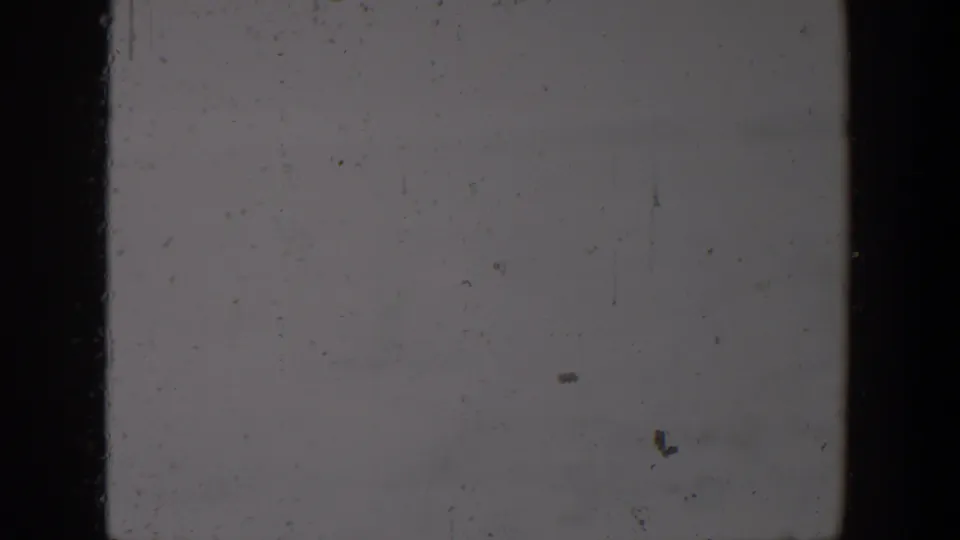 Blank 1957 Lubbock 8mm home-movie frame showing pale exposed film, dark gate borders, dust, scratches, and grain.