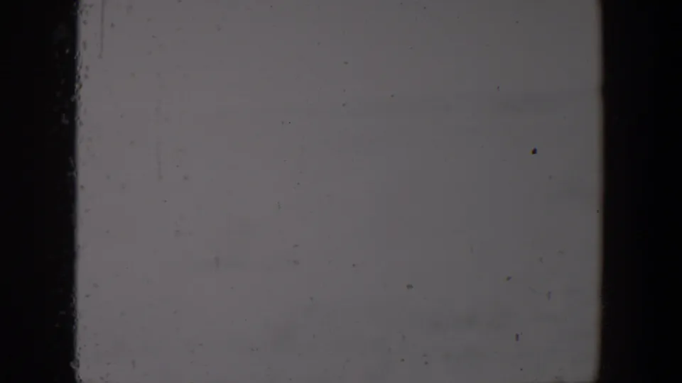 Blank lower portion of a 1957 Lubbock 8mm home-movie frame showing pale exposure, edge borders, dust, scratches, and grain.