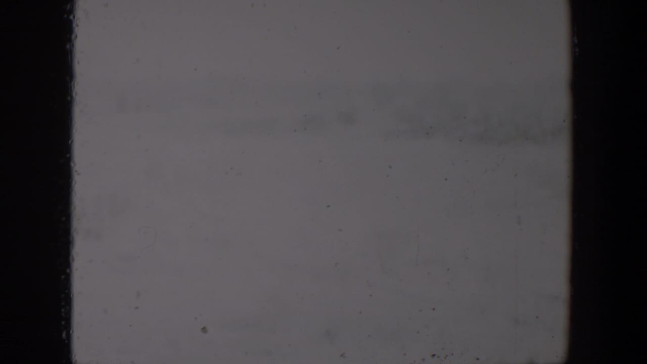 Soft, faded 8mm frame from the supplied 1957 Lubbock clip with little detail visible beyond an open outdoor setting.
