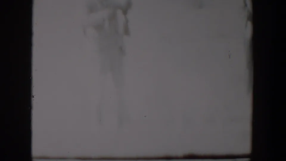 A muted 8mm frame from the Lubbock winter scene shows snow, faint vegetation, and an indistinct person or dog form at left.