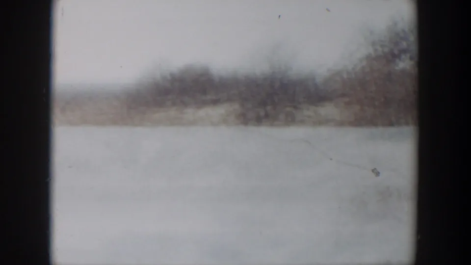 Open pastureland under a pale sky, with a distant tree line in this 1957 Lubbock 8mm frame.