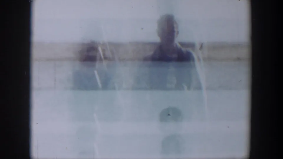 A distant figure is barely visible through pale overexposure and film haze in an open landscape, with the horizon faintly behind them.