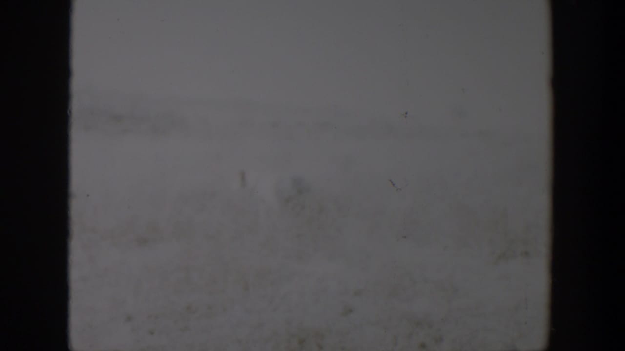 A soft, underexposed 8mm frame from the Lubbock, Texas clip shows mostly pale sky or film texture with dark gate borders.