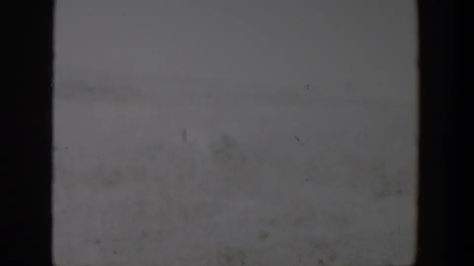 A soft, underexposed 8mm frame from the Lubbock, Texas clip shows mostly pale sky or film texture with dark gate borders.