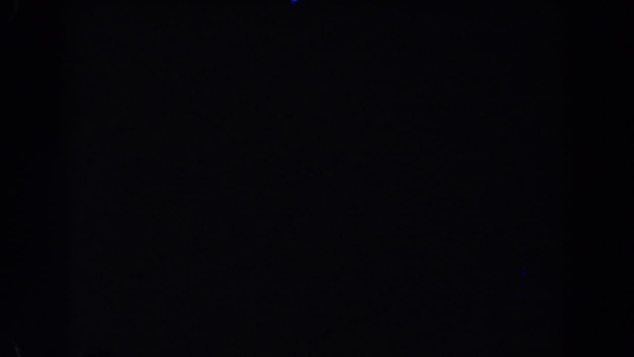 Very dark frame with faint blue light specks and barely visible vertical streaking.